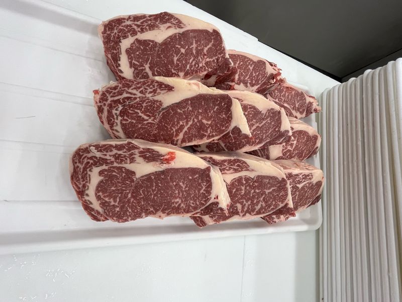Raw Akaushi Wagyu ribeyes with fine marbling laid out on a tray