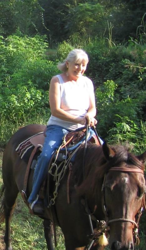 Merrill G. Frost, the matriarch of 4F, riding a bay Quarter Horse on a wooded trail